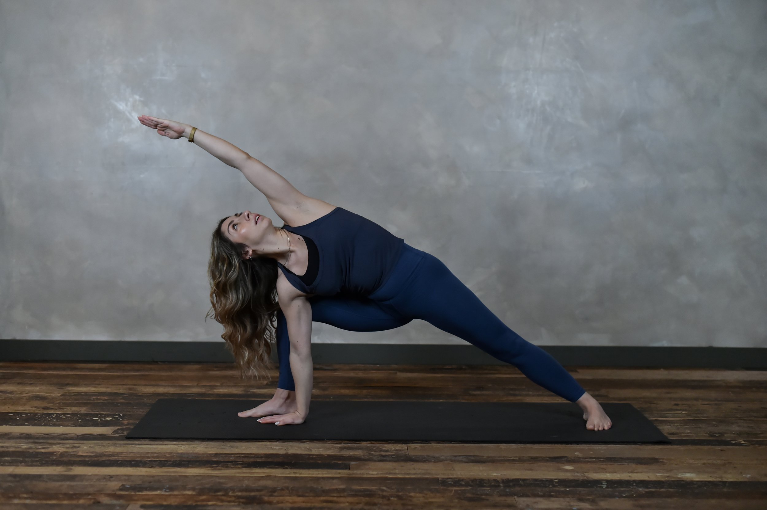 Marea Movement_A woman in navy blue stretches in an extended side angle pose